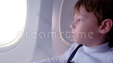 男孩在飞机上飞行时<strong>看</strong>着<strong>窗外</strong>。