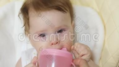 幼儿坐在幼儿座位上，从幼儿的杯子`喝水..