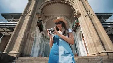 女专业摄影师戴墨镜帽，用相机彩色雕刻大门拍照
