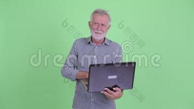 快乐的大胡子男人用笔记本电脑思考