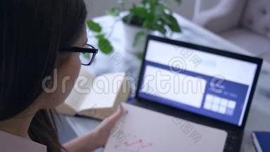 商务在线，戴眼镜的漂亮女孩用笔记本电脑，在笔记本电脑上写笔记，用红色标记