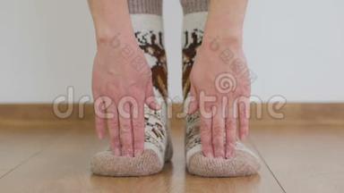 穿着温暖的羊毛袜子做体操的女人弯下腰，用手指触摸地板。