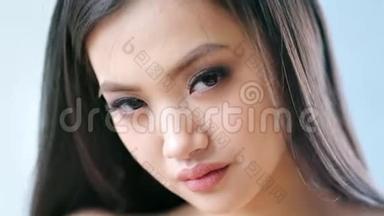 迷人的亚洲时尚模特的特写肖像，淡褐色的眼睛和长长的睫毛，慢动作