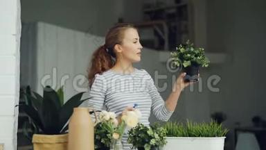 开朗的家庭主妇用喷雾器浇绿植物，拿着花盆，微笑着站在美丽的灯光下