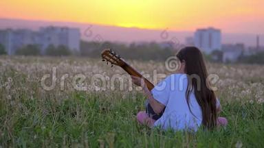 小女孩流行音乐家在城外练习吉他技巧。 在公园里弹吉他。 现场表演，训练，即兴表演