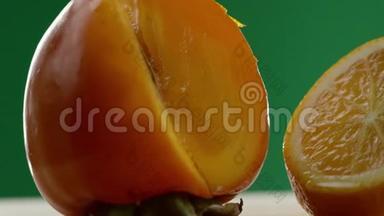 首先我们看到一个柿子，然后视频从左到右移动，我们看到一个橘子切成碎片，绿色的背景
