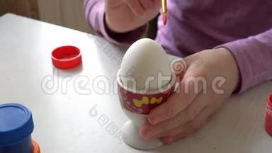 白鸡蛋站在桌子上的一个支架上，孩子开始用画笔在上面画.. 快关门。 4K. 25fps