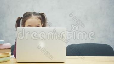 快乐可爱的聪明<strong>女孩</strong>坐在桌子上的一叠书和笔记本电脑的肖像，复制空间。 教育与发展