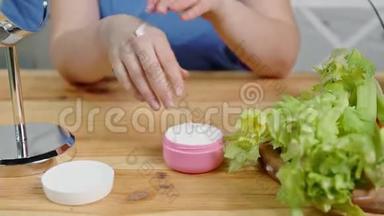 女人从罐子里取出保湿霜，擦手在桌子上