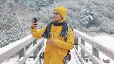 一位年轻的游客站在桥上使用智能手机。 他制作了sephi并在社交网络上发布了照片。 冬季