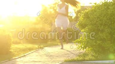 美丽的女孩在绿色公园的夏日里，在夕阳下<strong>奔跑</strong>着玩。 <strong>自由</strong>，健康，幸福的理念.. 快乐
