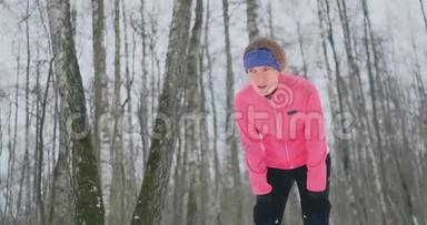 一个年轻的女人在冬天的森林里晨跑，累了，停下来休息，继续跑。 他恢复了体力