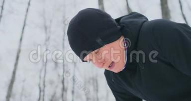 一个年轻人在冬天的森林里晨跑，累了，停下来喘口气。 他恢复了<strong>体力</strong>