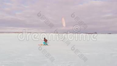 日落时，一个人正在雪地里滑雪. 他的降落伞拉。 在雪地里风筝冲浪...
