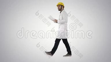 工程师经理带着安全帽走路，拿着纸，检查梯度背景。