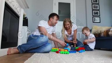 <strong>幸福</strong>的家庭爸爸妈妈和宝宝在他们明亮的客厅里玩乐高。 慢镜头拍摄<strong>幸福</strong>家庭