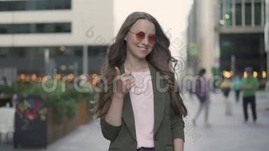 一个年轻漂亮的女人在秋天的街道上竖起大拇指