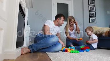 幸福的家庭爸爸妈妈和宝宝在他们明亮的客厅里玩乐高。 慢镜头拍摄幸福家庭