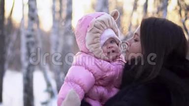 在冬天的户外，为年轻快乐的母亲和快乐的孩子做特写。 穿着粉色连衣裙的小女孩在妈妈手`微笑