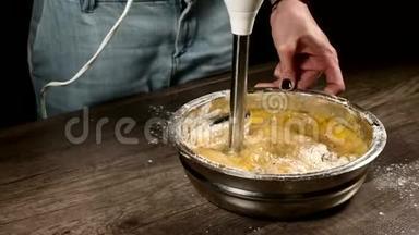 厨房里的一个糕点女孩在一个金属碗里用搅拌机<strong>打</strong>着<strong>面</strong>团做海绵蛋糕、<strong>面</strong>粉、鸡蛋和