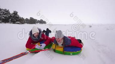 冬天穿红色夹克的孩子们骑着充气雪管和雪橇在雪中穿行。运动女孩放松