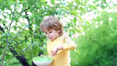 小男孩在加顿吃早餐。 快乐的小男孩勺子在户外吃。 宝宝吃天然绿色食物