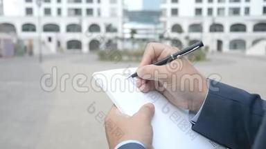 城市视野中的商人在纸质笔记本上记笔记