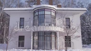 外观美丽的白色现代设计家居在冬天的雪树和蓝色的晴空背景。 库存录像。 二.