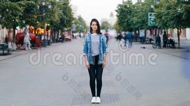紧张的年轻女子独自站在市中心，穿着牛仔裤和牛仔夹克，看着她的照片