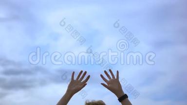 人的双手被高<strong>高举</strong>起在蓝天的背景下，自由的概念. 艺术。 戴着手表的人