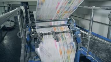 报纸页在印刷办公室的机械传送带上滚动。