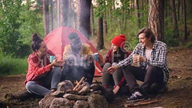 一群多民族的朋友，女孩和男人围坐在森林里，喝着饮料