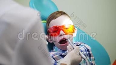儿童`牙医用橙色安全眼镜<strong>对待</strong>坐在椅子上的男孩