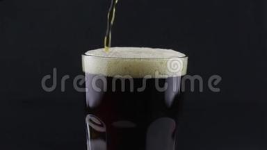 酒保把黑啤酒从瓶子里倒入玻璃杯里。 一个人把一杯黑啤酒装满。