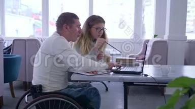 残疾人教育、女教师眼镜为坐轮椅的残疾人男子使用笔记本电脑上课