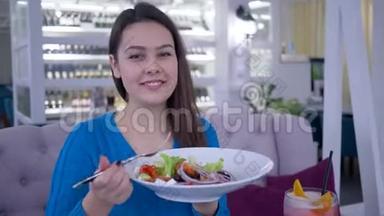 快乐的女人节食，微笑的女人一边吃蔬菜晚餐，一边从大盘子里吃漂亮有用的沙拉