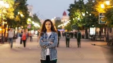 一幅时光流逝的照片，孤独的年轻女子双臂交叉站在市中心的街道上，而此时正是男人和女人的<strong>聚集</strong>地