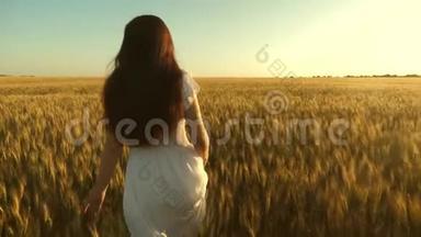 美丽的女孩走过一片成熟的小麦。 生态旅游。 女人拿着金色的<strong>麦子</strong>穿过田野