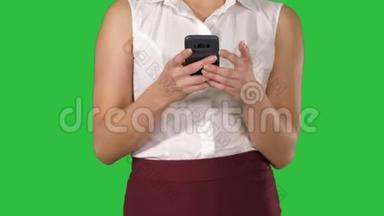 美丽的女人使用手机，女人手在智能手机上的绿色屏幕上发短信，Chroma键。