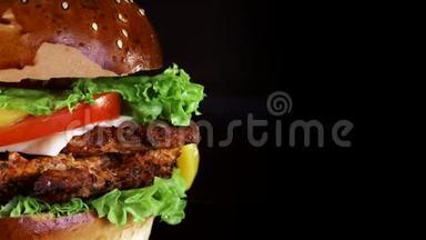汉堡特写，黑色背景木板上有大块的肉、绿色和奶酪