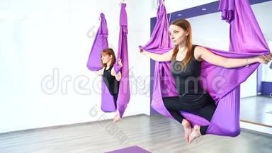 空中瑜伽课。年轻女子在吊床上练习瑜伽。