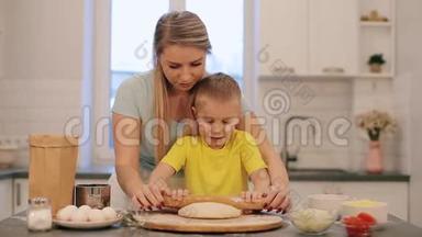 那个<strong>漂亮</strong>的金发小男孩帮<strong>妈妈</strong>做饭。 <strong>妈妈</strong>和儿子穿着五颜六色的衬衫，正在把面团卷出来。 <strong>妈妈</strong>是