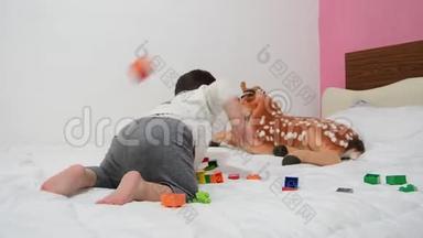一个半岁的男孩在床上<strong>玩乐</strong>高积木和软玩具