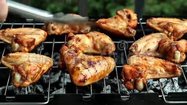 鸡翅烤架，人们用金属钳来转动一些辛辣的鸡翅，这些鸡翅正在烧烤