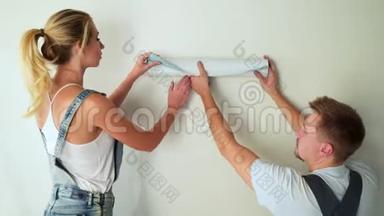 施工现场的年轻一对工人在<strong>墙上贴</strong>墙纸