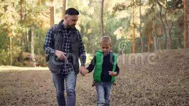 可爱的男孩正在森林里散步，他慈爱的父亲牵着他的手，蓄着胡子的年轻人正在说话和做手势