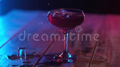 在脚的玻璃杯与红色鸡尾酒滴晶体透明冰冷。从玻璃杯里冒出来的方块。水花四溅