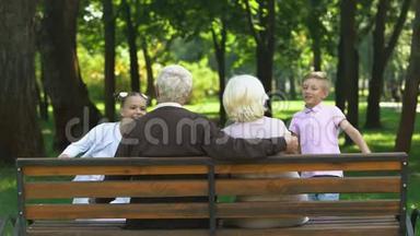 孙辈们<strong>跑到</strong>爷爷奶奶身边拥抱他们，在公园的长椅上休息