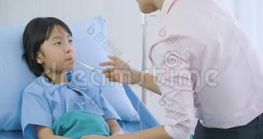 母亲在医院里测量她的小女儿的体温后看着体温计