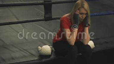 训练结束后，疲惫的少女坐在拳击台上